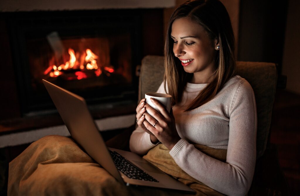 Woman using laptop near fireplace